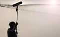 Sound boom operator recording sound by microphone fisher for movie set in a studio