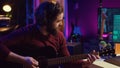 Sound engineer playing acoustic guitar and using mixing console to record music