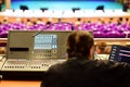 Sound engineer sits at a music console in a concert hall