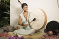 Sound healing and meditation therapy - attractive and elegant Asian Chinese healer woman playing drum at yoga studio as relaxation