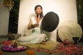 Sound healing and meditation therapy - attractive and elegant Asian Chinese healer woman playing drum at yoga studio as relaxation