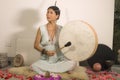 Sound healing and meditation therapy - attractive and elegant Asian Chinese healer woman playing drum at yoga studio as relaxation