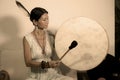 Sound healing and meditation therapy - attractive and elegant Asian Chinese healer woman playing drum at yoga studio as relaxation