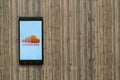 Soundcloud logo on smartphone screen on wooden background.