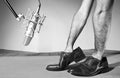 Man hands inside male dress shoes front a professional microphone and over a wood table. FC Royalty Free Stock Photo