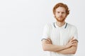 Sounds suspicious. Portrait of doubtful unsure good-looking redhead male student with beard in white polo shirt crossing