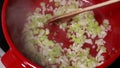 soup base mastery: cooking onion, garlic, and celery in a red pot close up