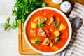 Soup with beef and vegetables in white plate on a wooden board. Traditional meat shurpa soup with vegetables and herbs, top view Royalty Free Stock Photo