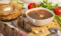 Soup, a plate of borscht with greens and sour cream, bread, pancakes, vegetables