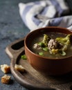 Soup with broccoli and meatballs in a brown Cup on a wooden stand.