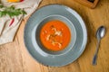 Soup cream of tomato on grey plate with greens on wooden table