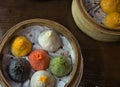 soup dumplings in a bamboo steam tray on wooden table (Xiaolongbao, xiao long bao) pork, colorful dough Shanghai