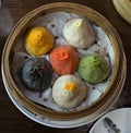 soup dumplings in a bamboo steam tray on wooden table (Xiaolongbao, xiao long bao) pork, colorful dough Shanghai