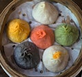 soup dumplings in a bamboo steam tray on wooden table (Xiaolongbao, xiao long bao) pork, colorful dough Shanghai