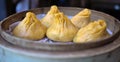 soup dumplings in a bamboo steam tray on wooden table (Xiaolongbao, xiao long bao) pork, colorful dough Shanghai