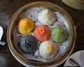 soup dumplings in a bamboo steam tray on wooden table (Xiaolongbao, xiao long bao) pork, colorful dough Shanghai