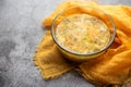 Soup kulesh with millet, potatoes and carrots in a clear bowl on an orange cloth.