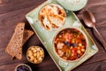 Soup with meat in bowl with oregano, chickpeas, peppers and vegetables served with crackers and bread on dark wooden background Royalty Free Stock Photo