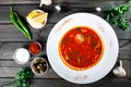 Soup with meat, olives, herbs and lemon in plate, served with sour cream, peppers on dark wooden background Royalty Free Stock Photo