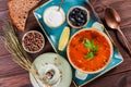 Soup with meat, olives, herbs, lemon, sour cream in bowl, black bread and spices on dark wooden background, homemade food Royalty Free Stock Photo