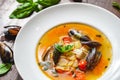 Soup with mussels and vegetables in white plate on wooden table Royalty Free Stock Photo