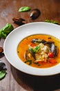 Soup with mussels and vegetables in white plate on wooden table. Royalty Free Stock Photo