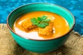 Soup of pumpkin puree and small croutons on a blue background. Close-up. Concept of the autumn menu. Royalty Free Stock Photo
