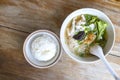 Soup with thin noodle, pock, pock stick, mushroom, vegetable in white bowl near have rice in small bowl on wood table. with copy