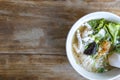 Soup with thin noodle, pock, pock stick, mushroom, vegetable in white bowl on wood table. with copy space for text or design