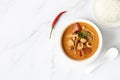 Soup Tom Yum Kung or with shrimp, chili pepper, jasmine rice and Asian spoon in a white plate on a marble background. Royalty Free Stock Photo