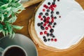 Sour cream cake, topped with berries with a hot cup of coffee