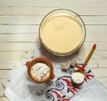 Sourdough dough in a bowl, flour in a wooden spoon on a tablecloth with embroidery, top view Royalty Free Stock Photo