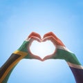 South Africa flag on woman hands in heart shape isolated on blue sky background for national unity, union, love and reconciliation