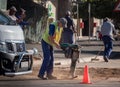 A South African road worker uses an earth compactor.