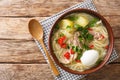 South American Caldo de Gallina chicken noodle soup with boiled egg and herbs close-up in a plate. horizontal top view