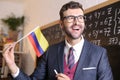 South American educator holding the Colombian flag in classroom