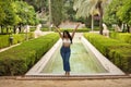 South American woman, young, beautiful, brunette, with crochet top and jeans standing next to a fountain, arms up, triumphant and