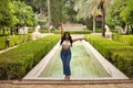 South American woman, young, beautiful, brunette, with crochet top and jeans standing next to a fountain, arms up, triumphant and