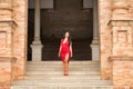 South American woman, young, beautiful, brunette, with an elegant red dress, posing as a model in the square of Spain in Seville. Royalty Free Stock Photo