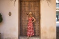 South American woman, young, pretty, blonde with flower dress, sunglasses and hat, posing in the middle of a wooden door. Concept