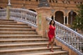 South American woman, young, pretty, brunette, in an elegant red dress, walking down a staircase, happy and contented in the Royalty Free Stock Photo