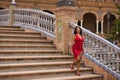 South American woman, young, pretty, brunette, in an elegant red dress, walking down a staircase, happy and contented in the Royalty Free Stock Photo