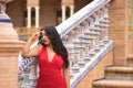 South American woman, young, pretty, brunette, wearing an elegant red dress, leaning on a railing with her eyes closed, sad and