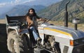 A south asian bearded and long haired man looking at camera while driving an old tractor in hilly area Royalty Free Stock Photo
