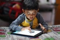 South Asian little boy drawing with fingers on a touch tablet Royalty Free Stock Photo