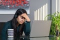 South Asian woman having a stressful business call in headphones at a desk in home office