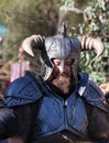 A man in a metal helmet with big horns looking at camera, a part of a costume performance of local medieval fair, community event Royalty Free Stock Photo