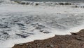 Tthe incoming sea foam rushing up the beach in south east Cornwall