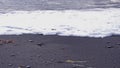 Tthe incoming sea foam rushing up the beach in south east Cornwall