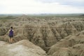 Young woman holding a phone stands at the edge of a rock formation in Badlands National Park to